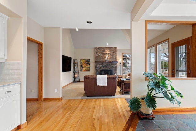 living room featuring lofted ceiling, a fireplace, and light hardwood / wood-style floors