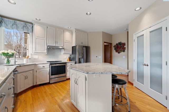 kitchen featuring a kitchen island, a breakfast bar area, light hardwood / wood-style floors, stainless steel appliances, and french doors