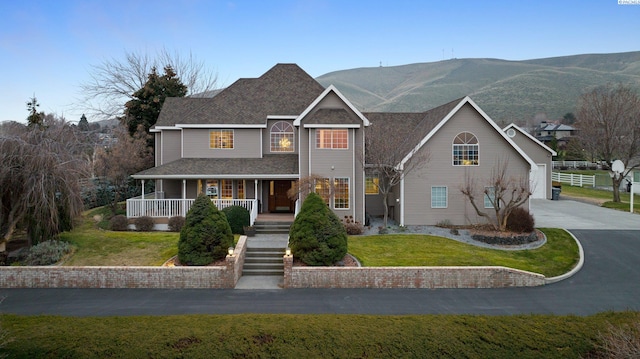 view of front property with a mountain view, a front yard, and covered porch