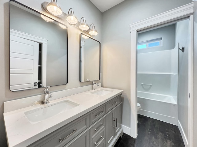 full bathroom with wood finished floors, a sink, toilet, and baseboards