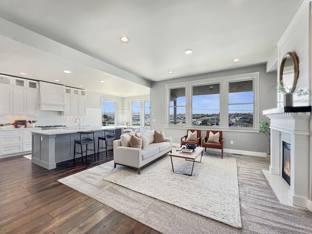 living area with dark wood-style floors, a fireplace with flush hearth, baseboards, and recessed lighting