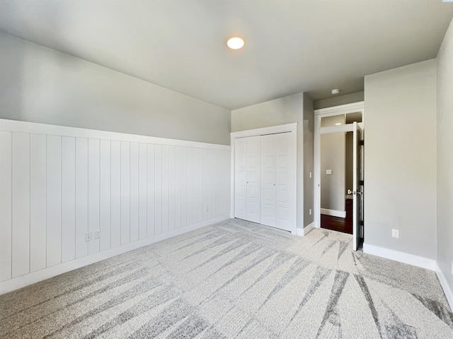 unfurnished bedroom featuring a closet, carpet flooring, and a wainscoted wall