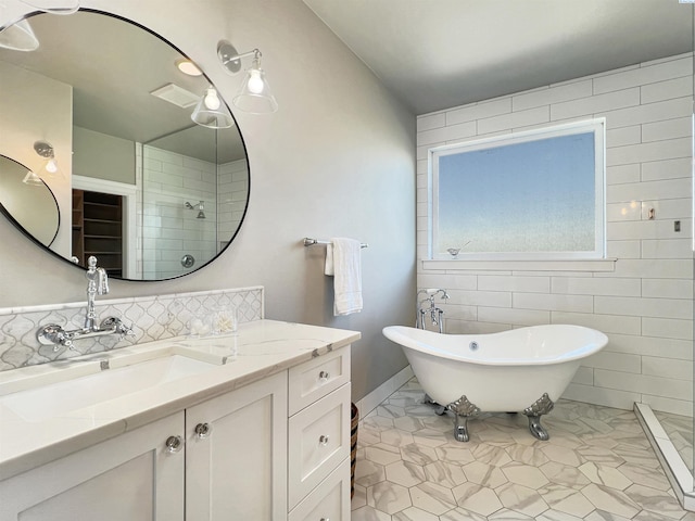 full bath featuring tile patterned flooring, a tile shower, a freestanding bath, vanity, and backsplash