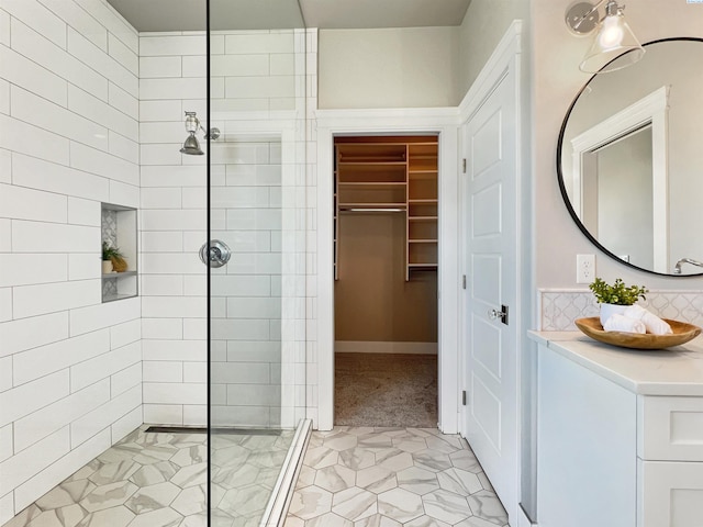 bathroom with a spacious closet, a walk in shower, backsplash, and vanity