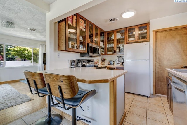 1706 Gaillard Pl, Richland, WA 99354 - kitchen featuring appliances with stainless steel finishes, a kitchen breakfast bar, light countertops, a peninsula, and glass insert cabinets
