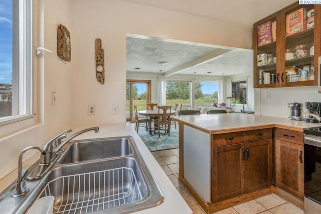 1706 Gaillard Pl, Richland, WA 99354 - kitchen with a sink, a peninsula, light tile patterned floors, light countertops, and glass insert cabinets