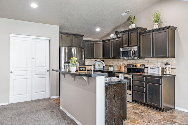 3313 Aqueduct Ln, Pasco, WA 99301 - kitchen with appliances with stainless steel finishes, dark countertops, baseboards, tasteful backsplash, and a kitchen island with sink