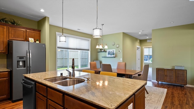 6102 Westmoreland Ln, Pasco, WA 99301 - kitchen with a center island with sink, appliances with stainless steel finishes, dark wood-type flooring, decorative light fixtures, and light stone countertops