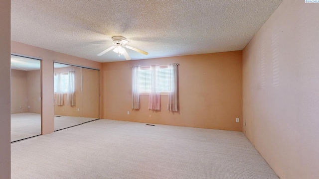 unfurnished bedroom featuring carpet, multiple closets, ceiling fan, and multiple windows