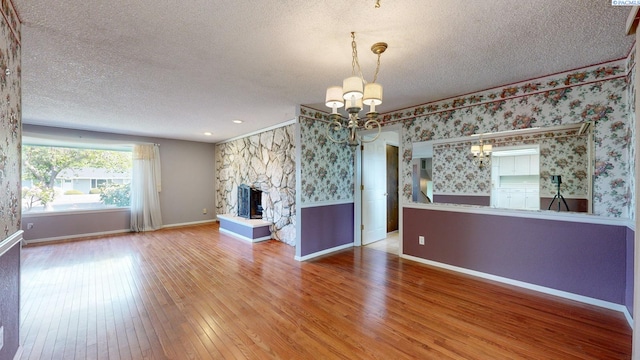 unfurnished living room with an inviting chandelier, hardwood / wood-style floors, and a textured ceiling