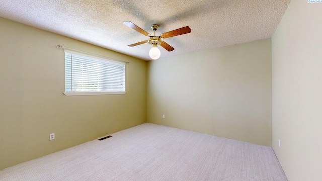 carpeted spare room with a ceiling fan, a textured ceiling, and visible vents