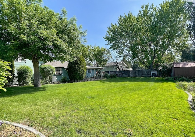 view of yard featuring fence, an outbuilding, and a storage shed