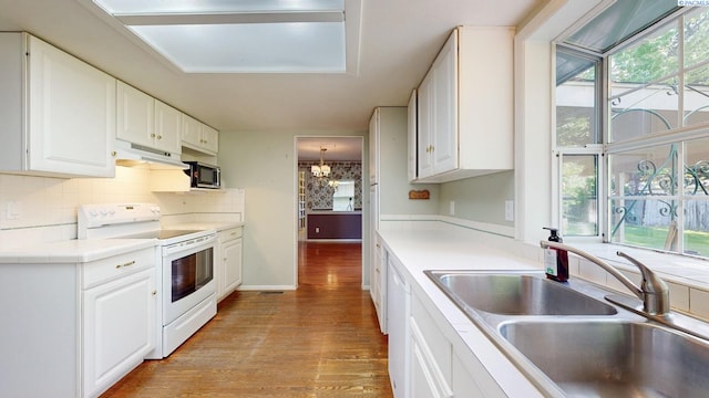 kitchen featuring light wood-type flooring, a sink, a healthy amount of sunlight, and white appliances