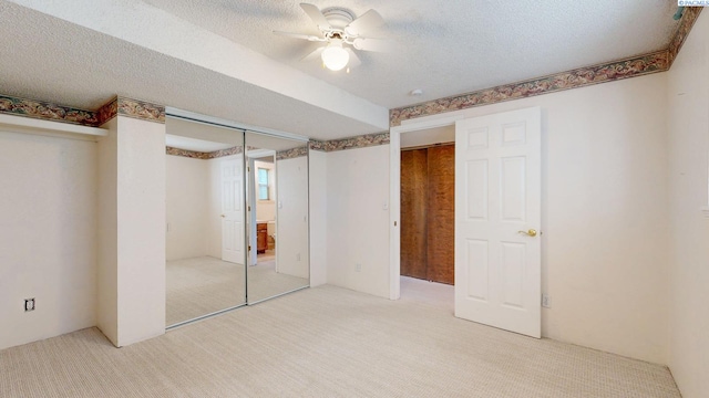 unfurnished bedroom with ceiling fan, a textured ceiling, and light colored carpet