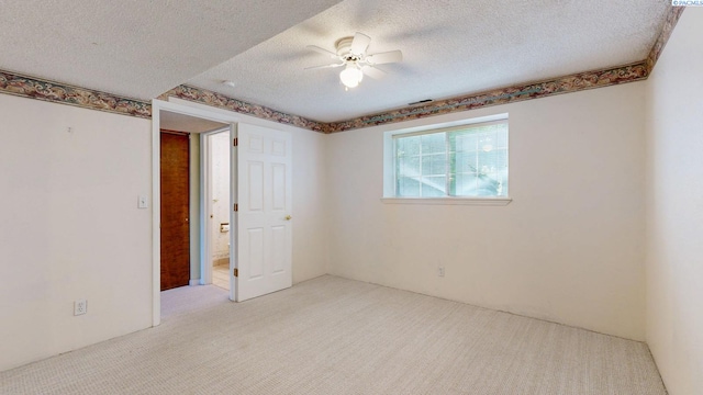 carpeted empty room featuring a ceiling fan, a textured ceiling, and visible vents