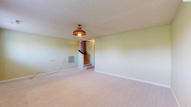 carpeted spare room featuring baseboards, visible vents, and stairway