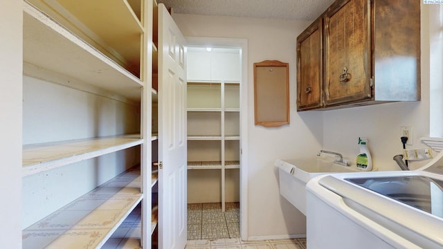 washroom with cabinet space, washer / clothes dryer, and a sink
