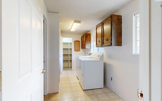 laundry room featuring a textured ceiling, light floors, cabinet space, and washing machine and dryer