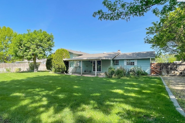 rear view of property featuring a lawn, a patio area, and fence