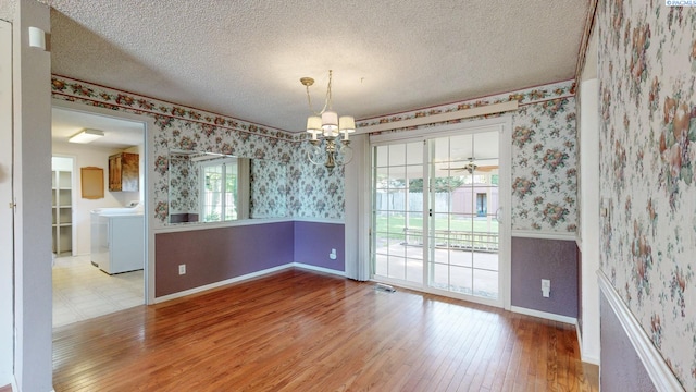 unfurnished dining area with an inviting chandelier, baseboards, light wood finished floors, washer / dryer, and wallpapered walls