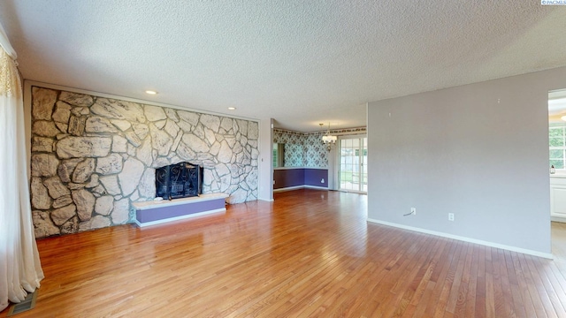 unfurnished living room with a healthy amount of sunlight, baseboards, light wood-type flooring, and a textured ceiling