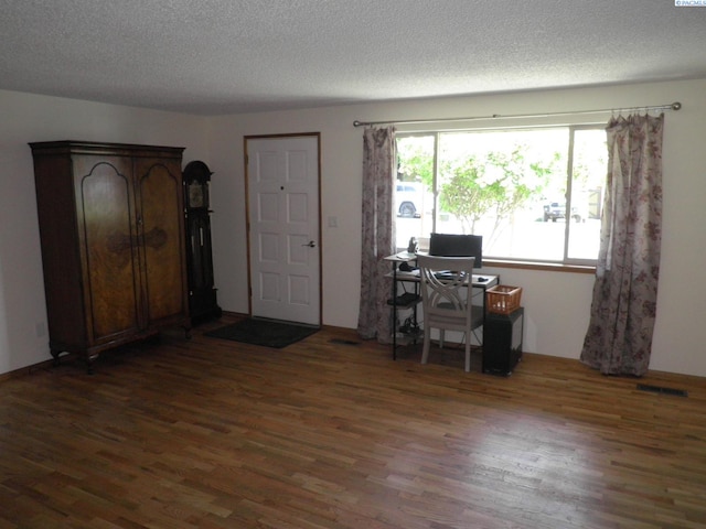 home office with dark hardwood / wood-style floors and a textured ceiling