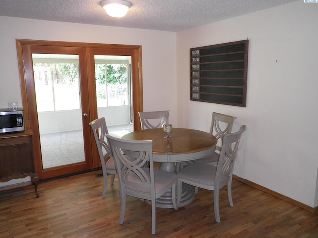 dining room with dark wood-type flooring and a textured ceiling