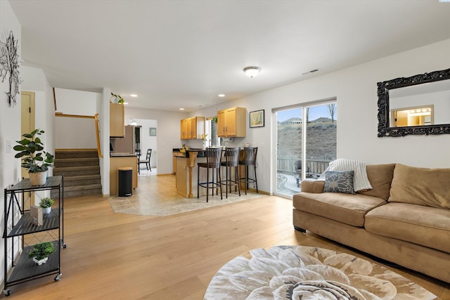 living room with recessed lighting, visible vents, stairway, light wood-type flooring, and baseboards