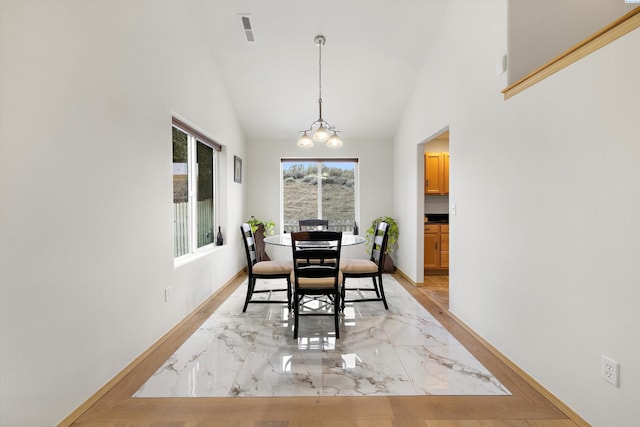 dining space featuring high vaulted ceiling, baseboards, visible vents, and a notable chandelier