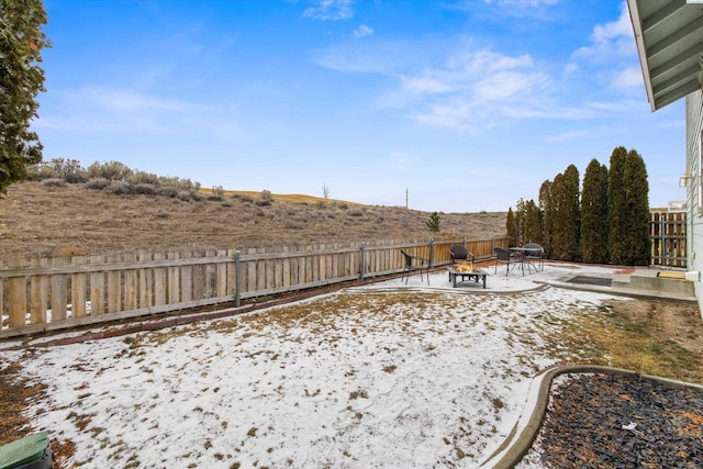 yard covered in snow featuring a fire pit, a patio area, and a fenced backyard