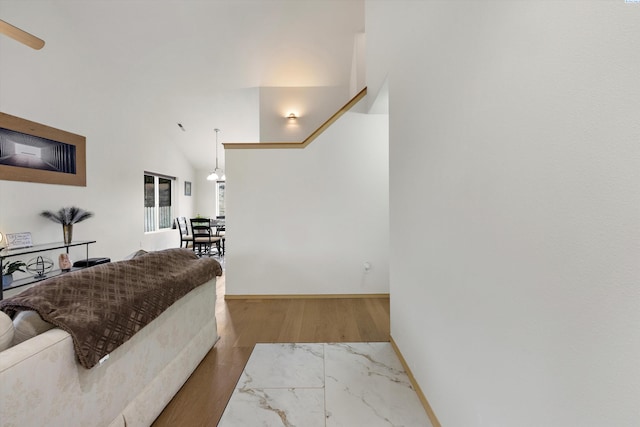 bedroom with high vaulted ceiling, wood finished floors, and baseboards