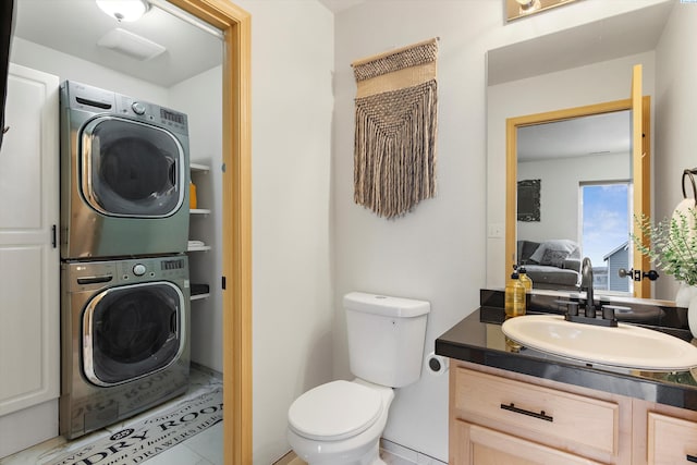 half bathroom featuring toilet, vanity, and stacked washer and clothes dryer