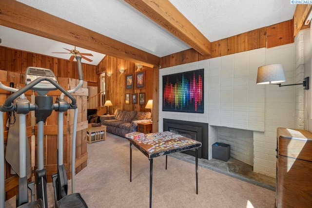 835 SE Spring St, Pullman, WA 99163 - carpeted living area featuring wood walls, beam ceiling, a glass covered fireplace, a ceiling fan, and a textured ceiling