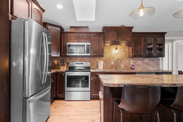 5504 Koufax Ln, Pasco, WA 99301 - kitchen featuring stainless steel appliances, a sink, light wood-style flooring, backsplash, and dark brown cabinetry