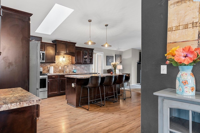 5504 Koufax Ln, Pasco, WA 99301 - kitchen with a skylight, a breakfast bar area, a sink, and light wood finished floors