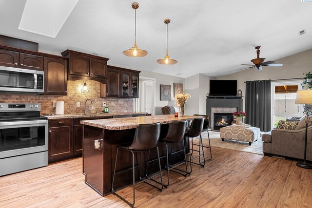 5504 Koufax Ln, Pasco, WA 99301 - kitchen featuring stainless steel appliances, vaulted ceiling, a sink, a kitchen bar, and decorative backsplash