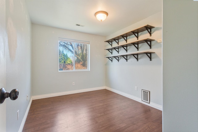 interior space with dark wood-type flooring, visible vents, and baseboards