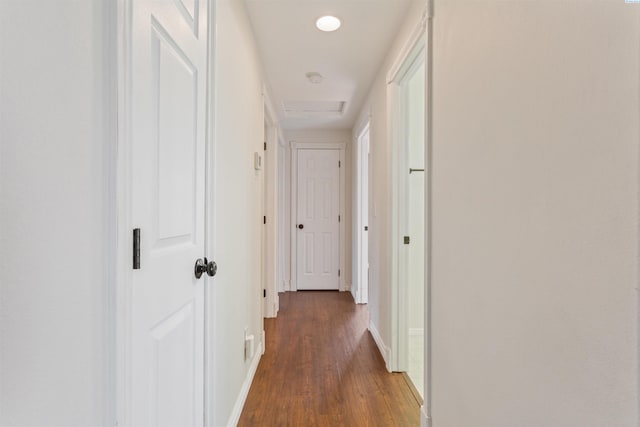 hallway with dark wood-style floors, attic access, and baseboards