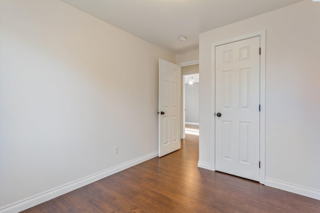 unfurnished bedroom with dark wood-type flooring and baseboards