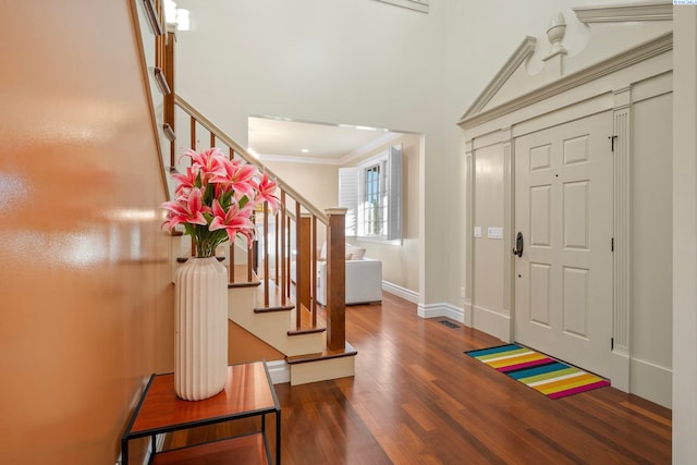 foyer entrance featuring stairway, wood finished floors, baseboards, and ornamental molding