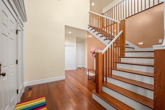 entryway with baseboards, stairs, recessed lighting, a high ceiling, and wood finished floors