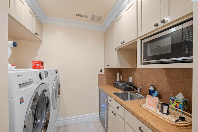 laundry room featuring visible vents, a sink, separate washer and dryer, crown molding, and laundry area