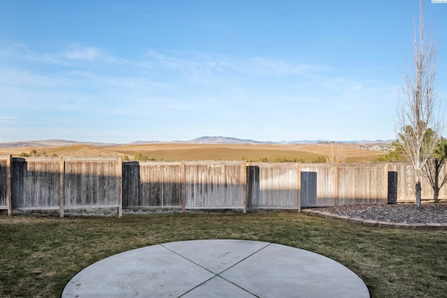 view of yard with a patio, a fenced backyard, and a mountain view