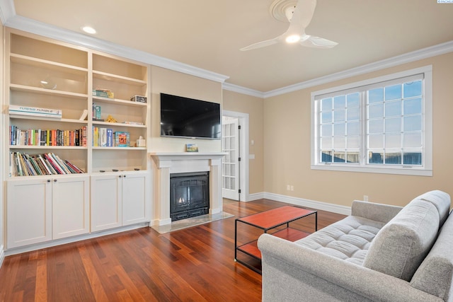 living room with dark wood-style floors, baseboards, a fireplace with flush hearth, ceiling fan, and crown molding