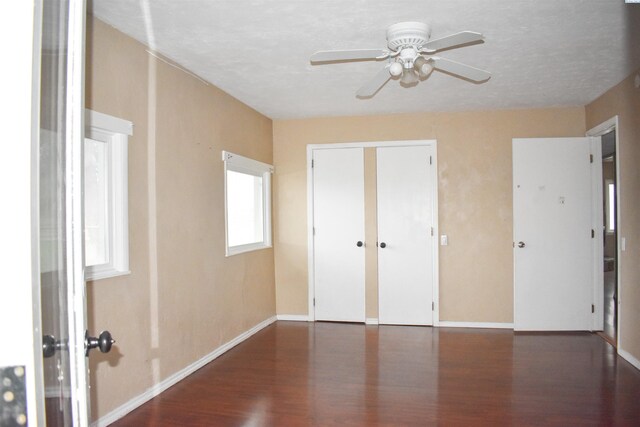 unfurnished bedroom with dark hardwood / wood-style flooring, ceiling fan, and a closet