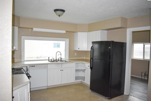 kitchen featuring sink, black refrigerator, white cabinetry, and dishwasher