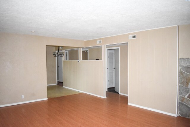 unfurnished room with a notable chandelier, wood-type flooring, and a textured ceiling