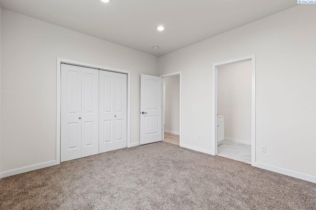 unfurnished bedroom featuring light carpet, ensuite bath, and a closet