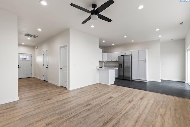 unfurnished living room featuring ceiling fan, sink, and light hardwood / wood-style floors