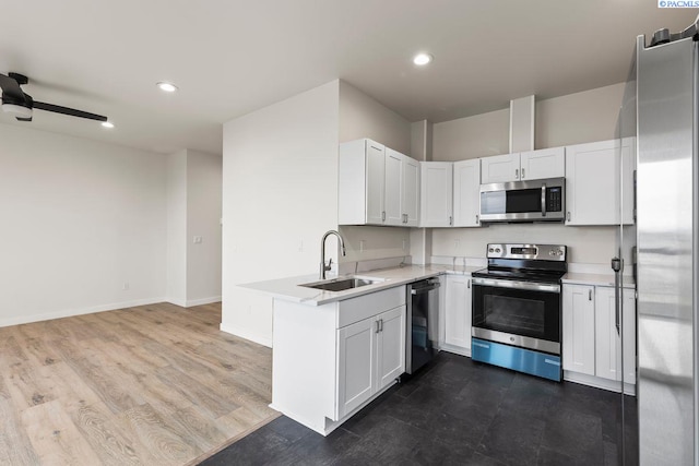 kitchen with sink, ceiling fan, stainless steel appliances, white cabinets, and dark hardwood / wood-style flooring